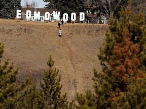 Passers-by check out an EDMOWOOD sign that popped up in Betty Stanhope-Cole Park, near 69 Street and Ada Boulevard, in Edmonton Wednesday March 31, 2021.