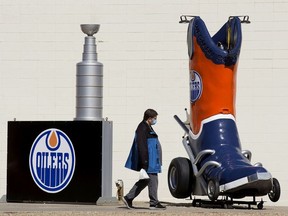 A pedestrian, wearing a mask to protect against COVID-19, makes their way past Edmonton Oilers decorations along 100 Avenue and 167 Street, in Edmonton Friday April 16, 2021. The Oilers April 16, 2021 game against the Vancouver Canucks has been postponed as the Canucks recover from a COVID-19 outbreak. Photo by David Bloom