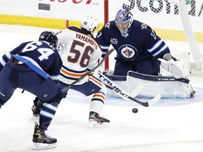 Winnipeg Jets defenseman Logan Stanley (64) chases down Edmonton Oilers right wing Kailer Yamamoto (56) as he shoots on goaltender Connor Hellebuyck (37) in the first period at Bell MTS Place on April 17, 2021.