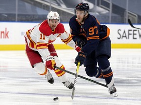 The Edmonton Oilers' Connor McDavid (97) battles the Calgary Flames' Mikael Backlund (11) during third period NHL action at Rogers Place, in Edmonton Thursday April 29, 2021. The Flames won 3-1.