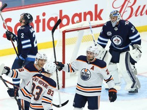 Edmonton Oilers forward Ryan Nugent-Hopkins (bottom centre) celebrates his second-period, power-play goal with Alex Chiasson (left) and Leon Draisaitl in Winnipeg on April 27, 2021.