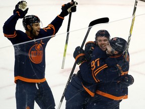 The Edmonton Oilers Connor McDavid (97) celebrates his 100th point with Leon Draisaitl (29) and Darnell Nurse (25) against the Vancouver Canucks at Rogers Place in Edmonton on Saturday, May 8, 2021.