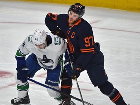 Edmonton Oilers Connor McDavid (97) gets knocked off the puck by Vancouver Canucks Quinn Hughes (43) during NHL action at Rogers Place in Edmonton, May 6, 2021.