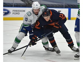 Edmonton Oilers Jesse Puljujarvi (13) and Vancouver Canucks Jayce Hawryluk (13) battle for the puck during NHL action at Rogers Place in Edmonton, May 15, 2021.