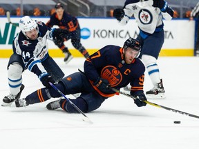 Edmonton Oilers' Connor McDavid (97) battles Winnipeg Jets' Josh Morrissey (44) during the first period of NHL North Division playoff action at Rogers Place in Edmonton, on Wednesday, May 19, 2021.