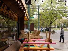 A diner in a COVID-19 mask picks up takeout at Remedy Cafe on 124 Street at 103 Avenue in Edmonton on Friday, May 28, 2021. The cafe’s patio tables were stacked up awaiting Alberta’s COVID-19 reopening plan’s Stage 1 on June 1, which will allow a maximum of four people per table outdoors with diners from within households or with two close contact for those living alone.