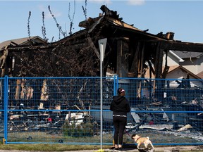A neighbour looks over fire damaged homes at 85 Street and 179 Avneue in Edmonton, on Saturday, May 29, 2021. Flames destroyed three homes and damaged others on May 28 in the city's Klarvatten neighbourhood. Photo by Ian Kucerak