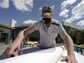 Mark Anthieren adorns some picnic tables with colourful art for patrons of Kingsway Mall on Monday May 31, 2021. Starting Tuesday June 1, 2021 diners will be able to enjoy some original artwork while eating in the parking lot outside the mall food court at a social distance that adheres to Alberta government pandemic health restrictions.