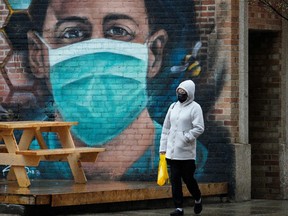 A woman walks past a wall mural in downtown Edmonton during the COVID-19 pandemic on Tuesday, May 18, 2021.