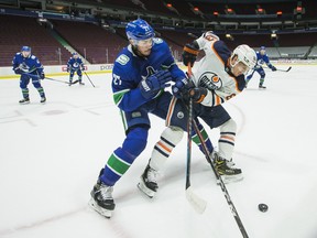 Vancouver Canucks defenceman Travis Hamonic (27) checks Edmonton Oilers forward Tyler Ennis (63) at Rogers Arena on Monday, May 3, 2021.