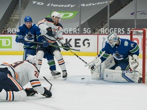 Vancouver Canucks goalie Thatcher Demko (35) makes a save on Edmonton Oilers forward Leon Draisaitl (29) as Canucks defenseman Nate Schmidt (88) and Oilers forward Connor McDavid (97) jostle in front of the net at Rogers Arena on Tuesday, March 4, 2021.