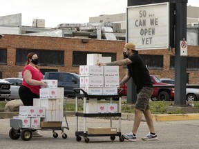 MKT Fresh Food | Beer Marke area general manager Sam Brabbins, right, and Delirium representative Crystal Armstrong load bar glasses outside MKT Fresh Food | Beer Market, 8101 Gateway Blvd., in Edmonton on Wednesday. May 26, 2021. On Wednesday Alberta announced it's reopening plan to remove COVID-19 restrictions.