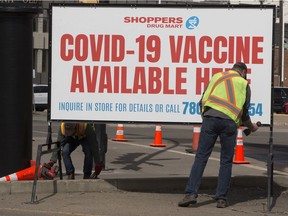 Crews set up a COVID-19 vaccine sign outside a Shoppers Drug Mart, 8065 104 St., in Edmonton Wednesday May 5, 2021. Albertans as young as 12 will qualify to book a COVID-19 vaccine appointment starting on Monday and those 30 and older can book starting Thursday. Photo by David Bloom