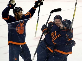 The Edmonton Oilers' Connor McDavid (97) celebrates his 100th point with Leon Draisaitl (29) and Darnell Nurse (25) against the Vancouver Canucks at Rogers Place in Edmonton on May 8, 2021.