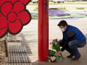 Boyle Street's executive director Jordan Reiniger arranges three bundles of flowers at a memorial in Kinistinâw Park, 96 Street and 103 Avenue in Edmonton on Tuesday, May 25, 2021. Ambulance crews were called to the park May 21, 2021, where they found three people in medical distress. Paramedics determined they were in cardiac arrest and tried to resuscitate them, but all three died at the scene.