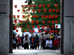 Orange fabric cut in the shape of shirts are pinned to string at the Human Right's Monument in Ottawa, during a vigil held by Ottawa faith communities, to honour the 215 children whose remains were found at the grounds of the former Kamloops Indian Residential School at Tk’emlups te Secwépemc First Nation in Kamloops, B.C., on Saturday, June 5, 2021.