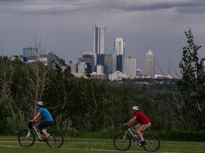 Cyclists ride in a stiff wind as a rain storm hits downtown, seen from Hardisty Drive in the Capilano neighbourhood of Edmonton, on Tuesday, June 15, 2021. Photo by Ian Kucerak