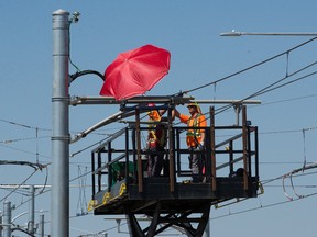 Crews use an umbrella in an attempt to create some shade as they work on the Valley Line LRT expansion, near 28 Avenue and 66 Street, in Edmonton Tuesday June 29, 2021. Environment Canada is forecasting temperatures in Edmonton to hit a high of 36 C, but the humidex could make it feel like 41 C.