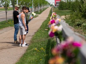 Crash witnesses and neighbours came out to place flowers at the site of a collision that killed a woman on Wednesday evening off 142 Street north of 153 Avenue in Edmonton, on Thursday, June 3, 2021. Police say charges are pending against the driver of the blue Subaru WRX car.