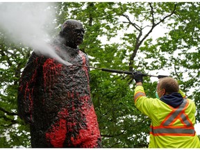 The statue of Sir Winston Churchill near city hall in Downtown Edmonton is washed on Thursday June 17, 2021, after it was vandalized with red paint.