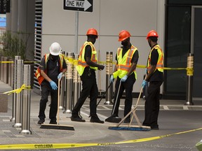 Workers clean up pieces of broken glass along 102 Street between 104 avenue and 103 avenue, that are from a pane of glass that fell from the Stantec Tower on Friday, June 25, 2021 in Edmonton.Greg Southam-Postmedia