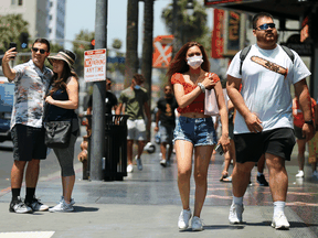 People walk and take photos on Hollywood Boulevard on June 15, 2021 in Los Angeles. California, the first state in the U.S. to go into lockdown at the beginning of the coronavirus pandemic, has lifted nearly all COVID-19 restrictions.