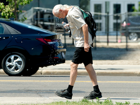 A pedestrian dumps water on his head to fight the heat while walking along 101 Street near 103A Avenue in Edmonton Monday, June 28, 2021.