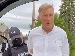 An RCMP officer arrests People's Party of Canada Leader Maxime Bernier for allegedly defying COVID restrictions, in St-Pierre-Jolys, Manitoba, on June 11, 2021.