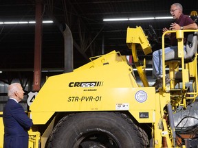 U.S. President Joe Biden speaks with Mike La Fleur (R), Superintendent of Streets for La Crosse MTU, as he sits on top of a road repair machine, during a tour of the La Crosse Municipal Transit Utility in La Crosse, Wisconsin, June 29, 2021, as he travels to promote his infrastructure plans. (