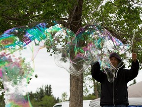 Neal Berlinguette with Yegbubbles has a hard time creating large bubbles with the strong gusts of wind on Thursday, June 17, 2021 at the Ottewell Community League Artisan Farmers' Market in Edmonton.