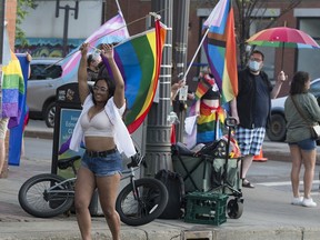 People dance and wave flags in front of street preachers at the corner of 104 Street and Jasper Avenue, in Edmonton Friday June 4, 2021.