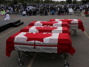 The caskets of four family members in London, Ont., killed in a racist attack are draped with Canadian flags during a funeral service on June 12, 2021.