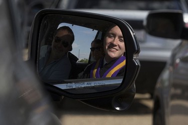 Nikolai Philipenko, 18, is reflected in a vehicle side mirror as he attends his drive-in graduation ceremony for Archbishop MacDonald High School, at the Edmonton EXPO Centre parking lot Friday June 4, 2021. The unorthodox ceremony was in response to COVID-19 health restrictions.