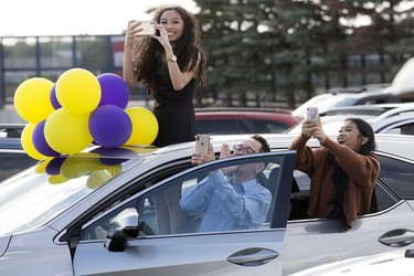 A family takes photos from their car during Archbishop MacDonald High School's drive-in graduation ceremony, at the Edmonton EXPO Centre parking lot Friday June 4, 2021. The unorthodox ceremony was in response to COVID-19 health restrictions.