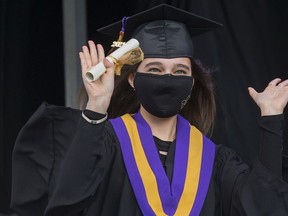 A student celebrates after receiving a diploma during Archbishop MacDonald High School's drive-in graduation ceremony at the Edmonton Expo Centre parking lot on June 4, 2021. The unorthodox ceremony was in response to COVID-19 health restrictions.