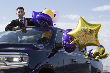 Raimond Delizo, 18, stands in the sunroof of a truck as he attends his drive-in graduation ceremony for Archbishop MacDonald High School, at the Edmonton EXPO Centre parking lot Friday June 4, 2021. The unorthodox ceremony was in response to COVID-19 health restrictions.