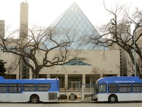 Edmonton city hall is visible behind parked Edmonton Transit Service buses on Jan. 19, 2021.