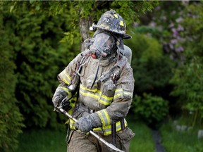 A firefighter emerges from a home after battling a residential house fire in southwest Edmonton on June 13, 2021.