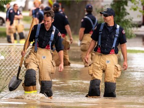 Edmonton Fire Rescue Service firefighters wade in high water as they respond to a water main break at 101 Street and 116 Avenue in Edmonton, on Sunday, July 4, 2021.