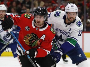 CHICAGO, ILLINOIS - MARCH 18: Duncan Keith #2 of the Chicago Blackhawks and Alexander Edler #23 of the Vancouver Canucks battle for position at the United Center on March 18, 2019 in Chicago, Illinois.