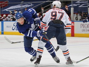 Connor McDavid (97) of the Edmonton Oilers holds up Zach Hyman (11) of the Toronto Maple Leafs at Scotiabank Arena on March 29, 2021, in Toronto.
