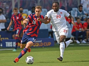James Sands (No. 16) of the United States controls the ball against Ayo Akinola (No. 20) of Canada during the first half of the 2021 CONCACAF Gold Cup match at Children's Mercy Park on July 18, 2021 in Kansas City, Kansas.