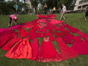 Self described Indigenous supporters use 51 dresses to create the outline of a giant red dress in honour of missing and murdered Indigenous women and girls at the Alberta legislature in Edmonton on July 29, 2021. The dress was part of a red dress photography project by photographer Mufty Mathewson.