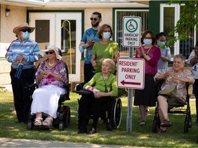Residents and caregivers of CapitalCare Laurier House Lynnwood watch as David Ghermezian of the Triple Five Group of Companies, which owns West Edmonton Mall, and Coun. Andrew Knack receive certificates of appreciation for their efforts in replacing the 170 Street pedestrian overpass during a ceremony outside the facility in Edmonton on Friday, July 9, 2021.