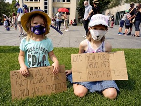 Wren Brayall, left, 4, and her sister Juliette Brayall, 7, joined approximately 200 people at a rally near the Alberta legislature on Friday, July 30, 2021, to protest the Alberta government's lifting of pandemic restrictions.