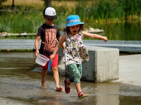 Fiona Ryan (3) and her brother Isaac (5) cool their heels at Paul Kane Park in Edmonton as temperatures rose to 32C degrees in the city on Wednesday July 14, 2021. Environment Canada has issued a heat warning for the region.