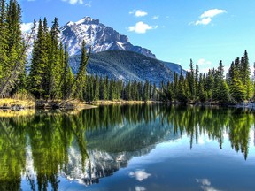 The Cascade Mountain is reflected in the Bow River at Banff National Park.