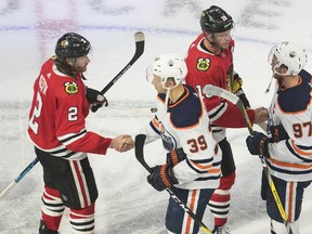 Edmonton Oilers' Alex Chiasson (39) and Connor McDavid (97) shake hands with Chicago Blackhawks' Duncan Keith (2) and Jonathan Toews (19) following the NHL qualifying round in Edmonton on August 7, 2020.