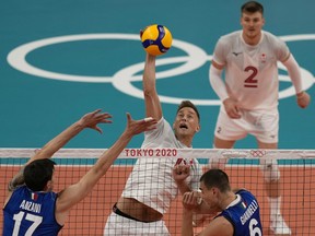 Canada's Lucas van Berkel spikes the ball past the Italian defence during their preliminary round pool A match between at the 2020 Summer Olympics, Saturday, July 24, 2021, in Tokyo, Japan.