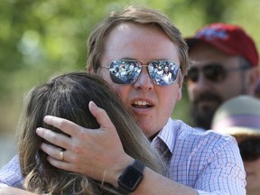 Alberta Health Minister Tyler Shandro hugs his wife Andrea after being heckled by protesters upon arrival with his family to celebrate the lifting of public health restrictions and Canada Day activities in Calgary, Alta., Thursday, July 1, 2021.